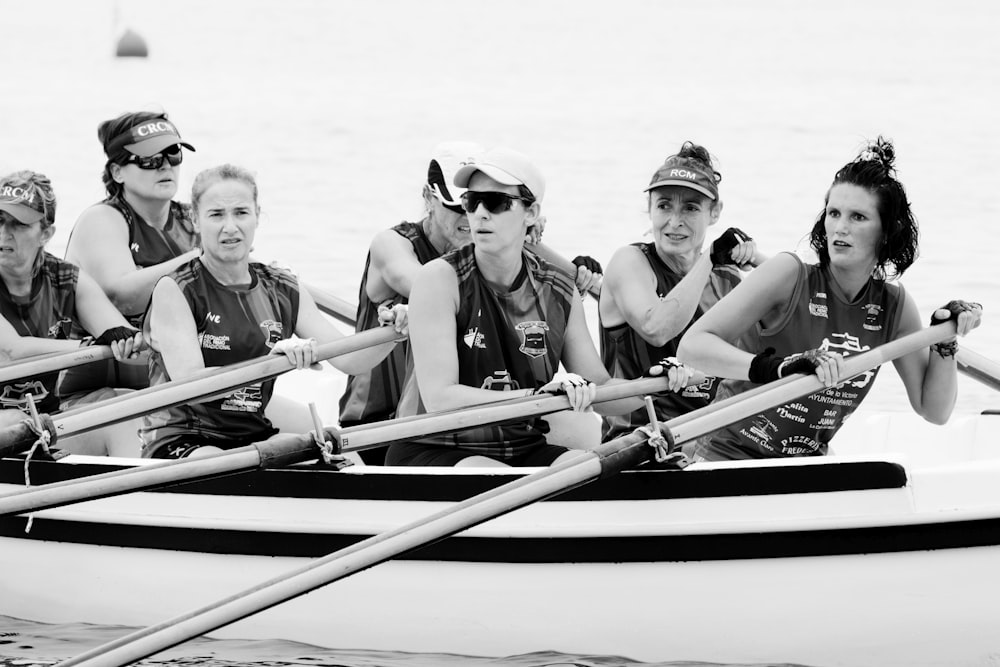 3 women in black and white shirts riding on blue and white boat on sea during