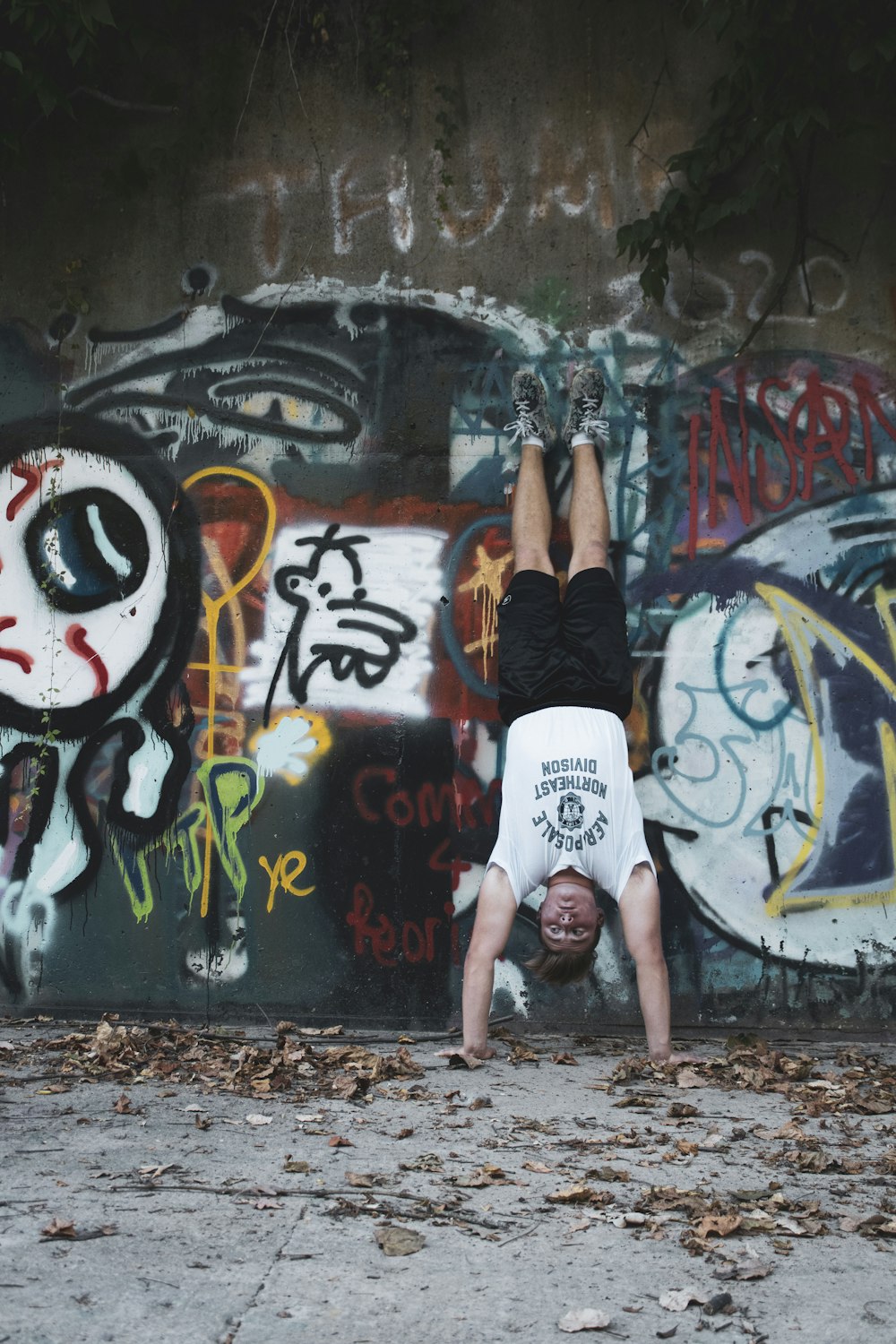 woman in black tank top and white shorts standing on graffiti wall