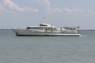 white and red ship on sea under white clouds during daytime