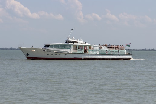 white and red ship on sea under white clouds during daytime