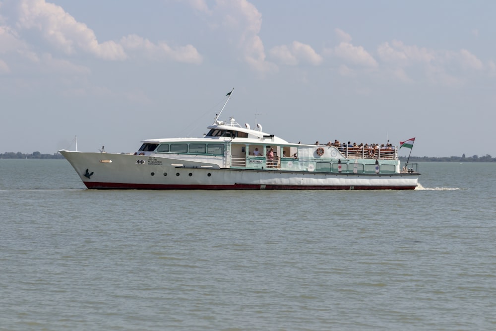 white and red ship on sea under white clouds during daytime