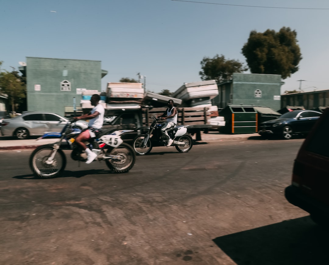 black and red motorcycle parked beside green building during daytime