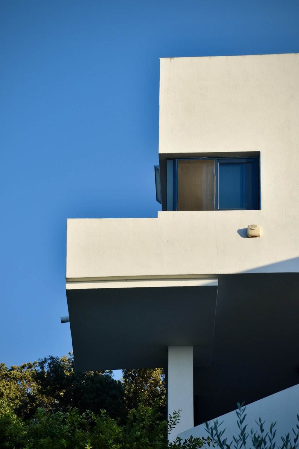 Weißes Betongebäude mit blauem Fenster