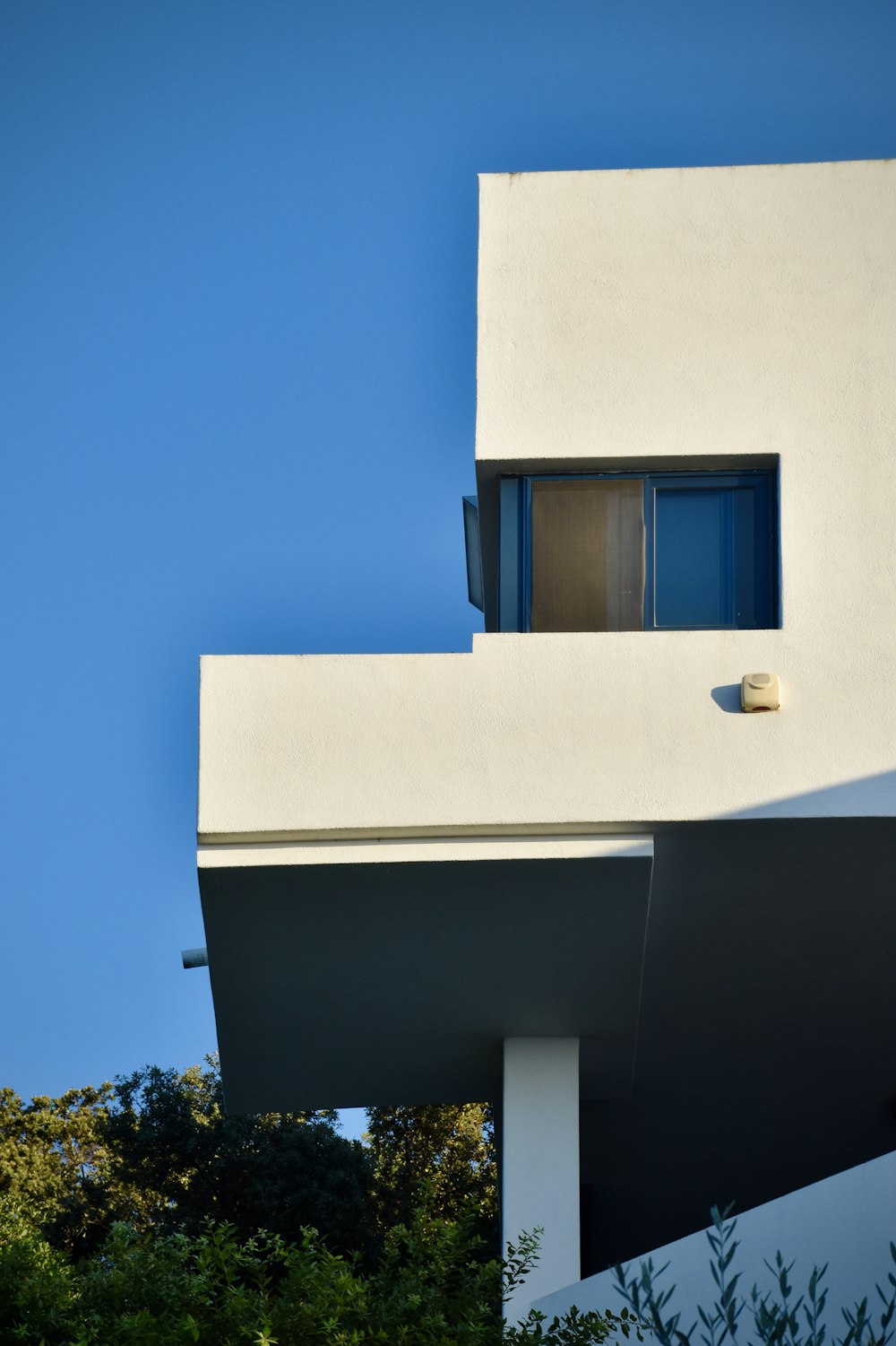 Bâtiment en béton blanc avec fenêtre bleue