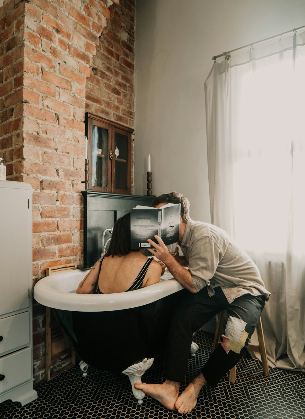 man in gray long sleeve shirt sitting on white ceramic bathtub