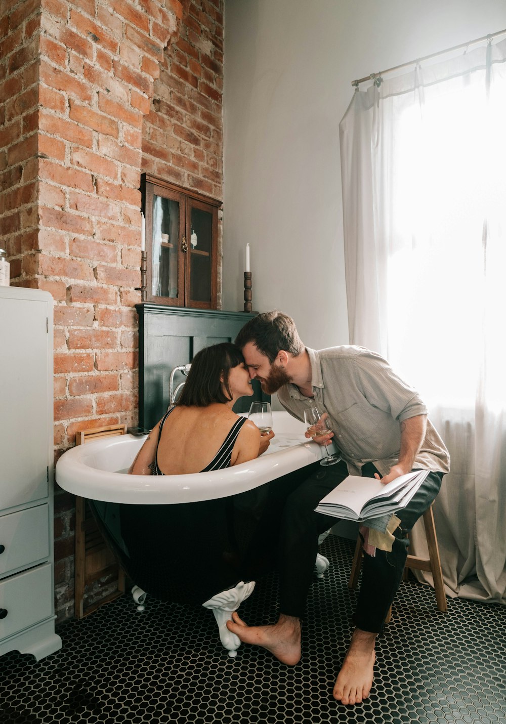 homem na camisa social cinza beijando a mulher no biquíni preto na banheira