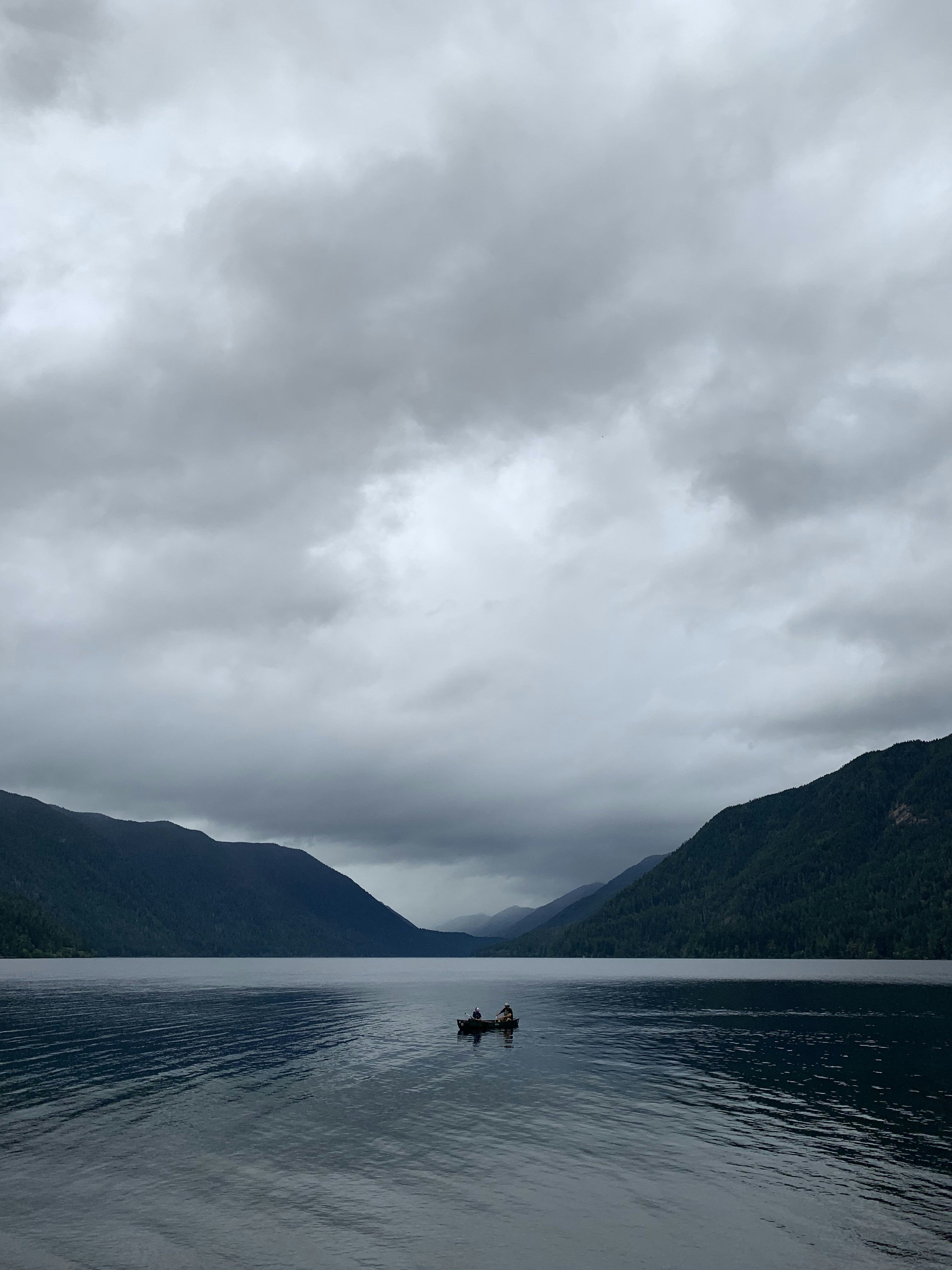 person riding on boat on sea near mountain under white clouds during daytime
