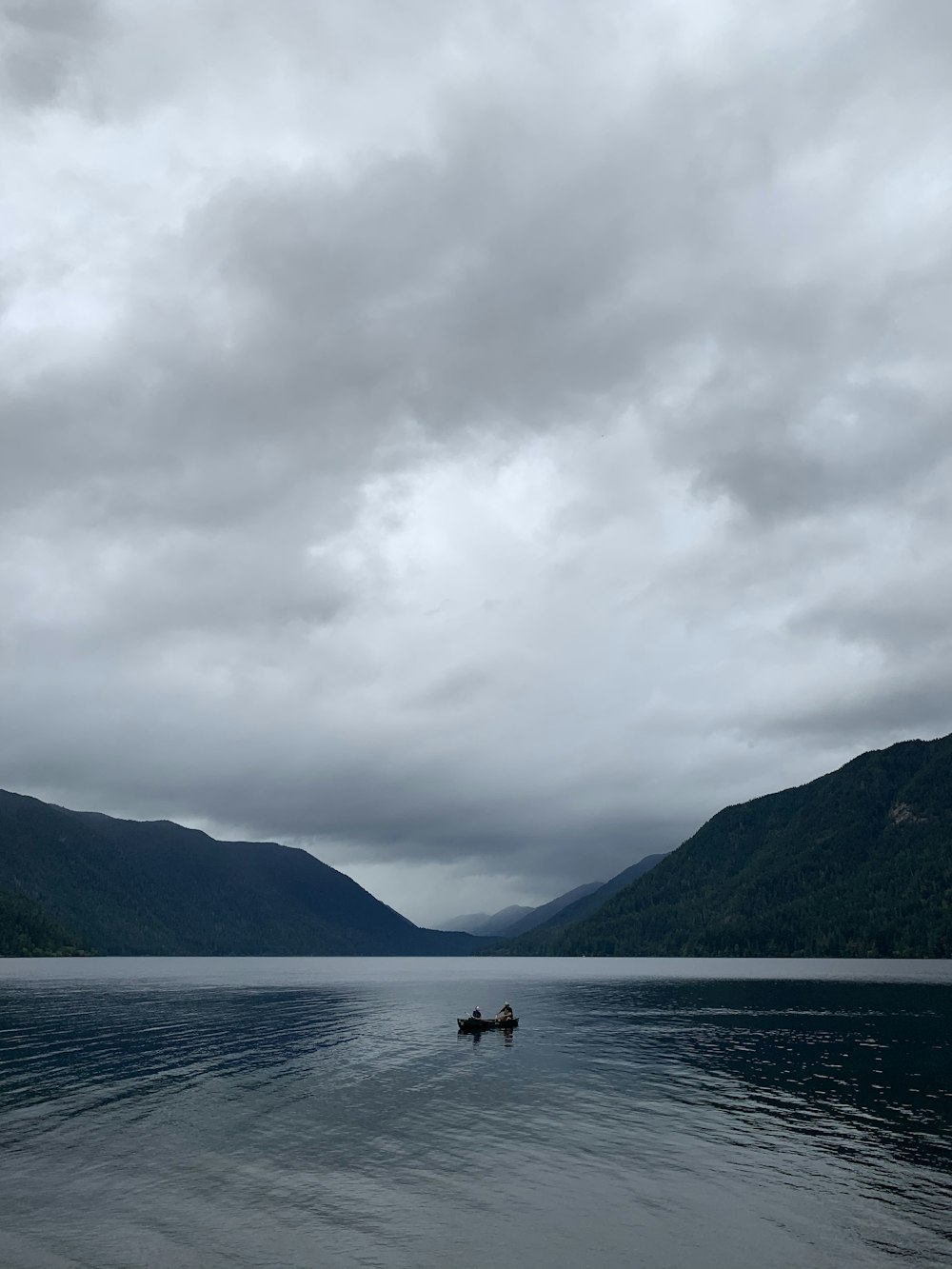 person riding on boat on sea near mountain under white clouds during daytime