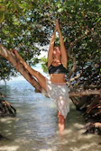 A graceful tree pose performed on a wooden deck surrounded by lush greenery.