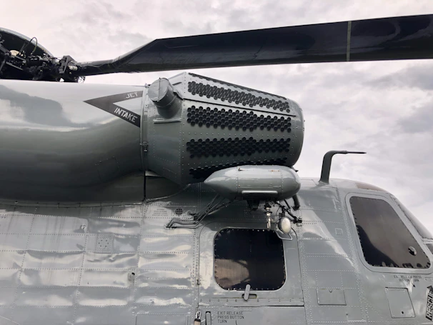 Close-up of a helicopter rotor blade being inspected by a technician in a hangar.