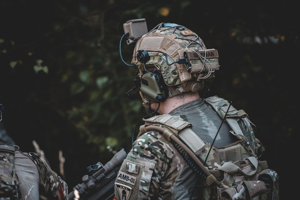 homem em jaqueta de camuflagem preta e marrom usando capacete e capacete