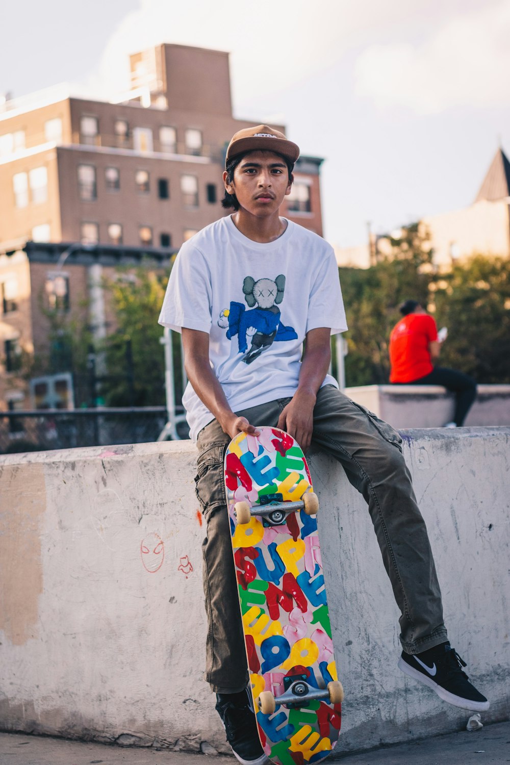 man in white crew neck t-shirt holding blue and red skateboard