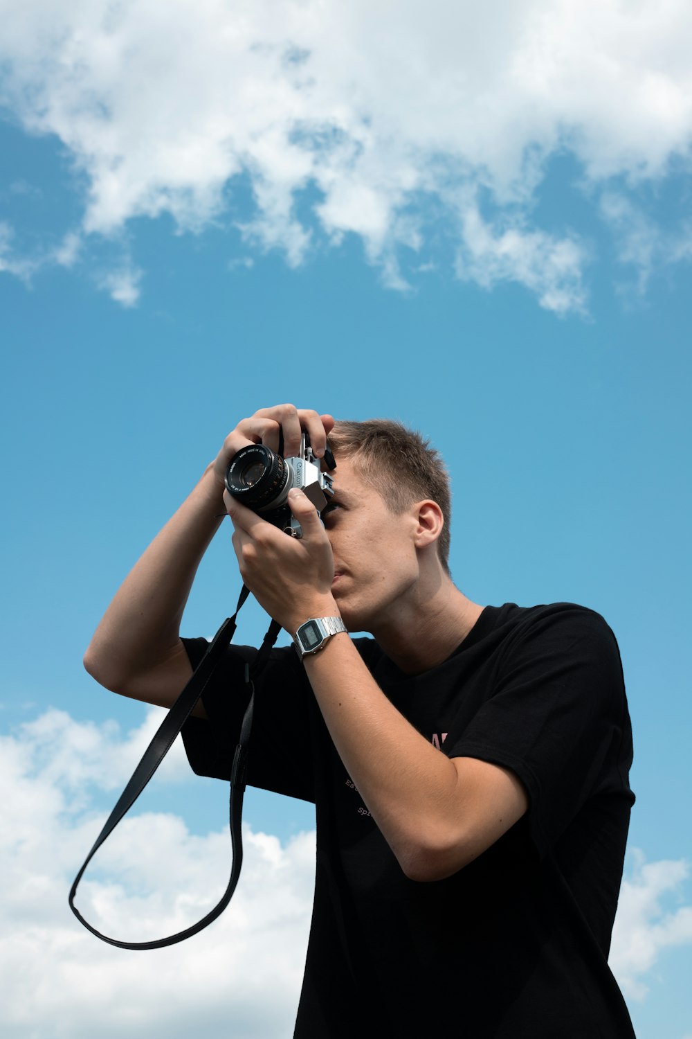 man in black crew neck t-shirt holding black dslr camera during daytime