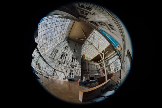 A photographer capturing a 360-degree image of a modern office building lobby.