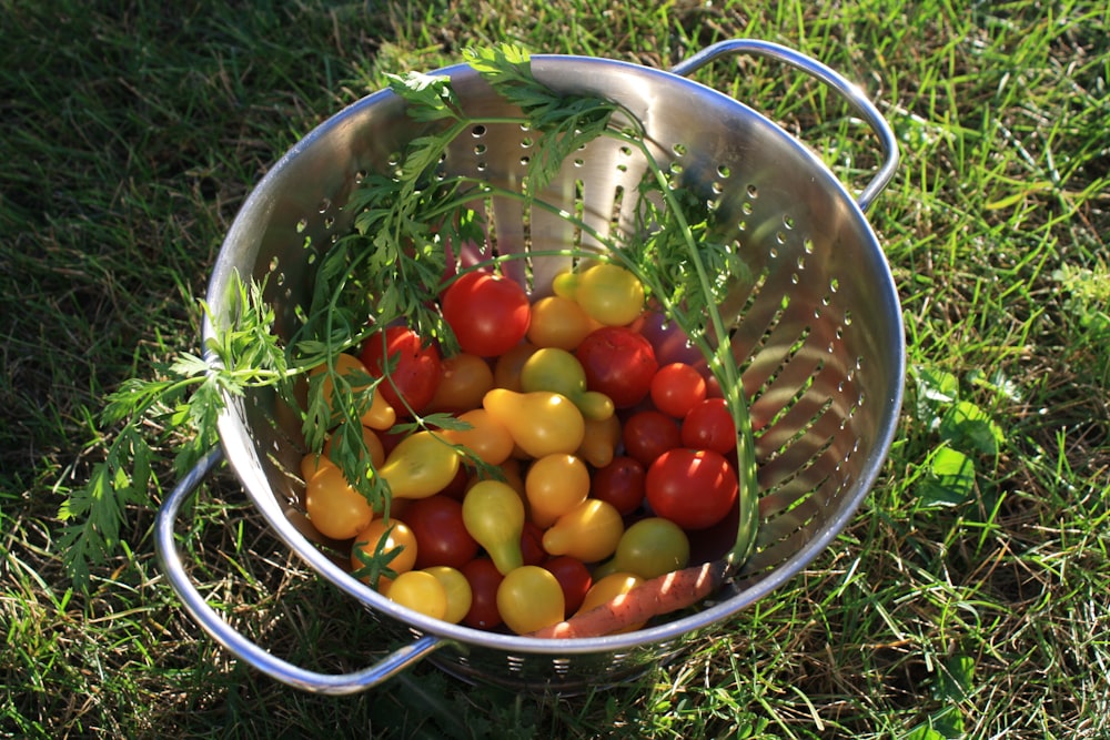 red and yellow round fruits in stainless steel bowl