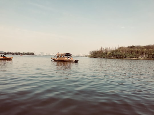 brown boat on body of water during daytime in Xihu China