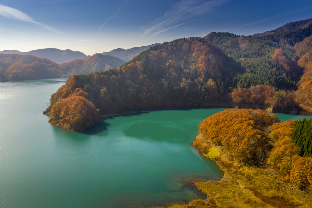 昼間の青空の下、青い湖のほとりの茶色と緑の山