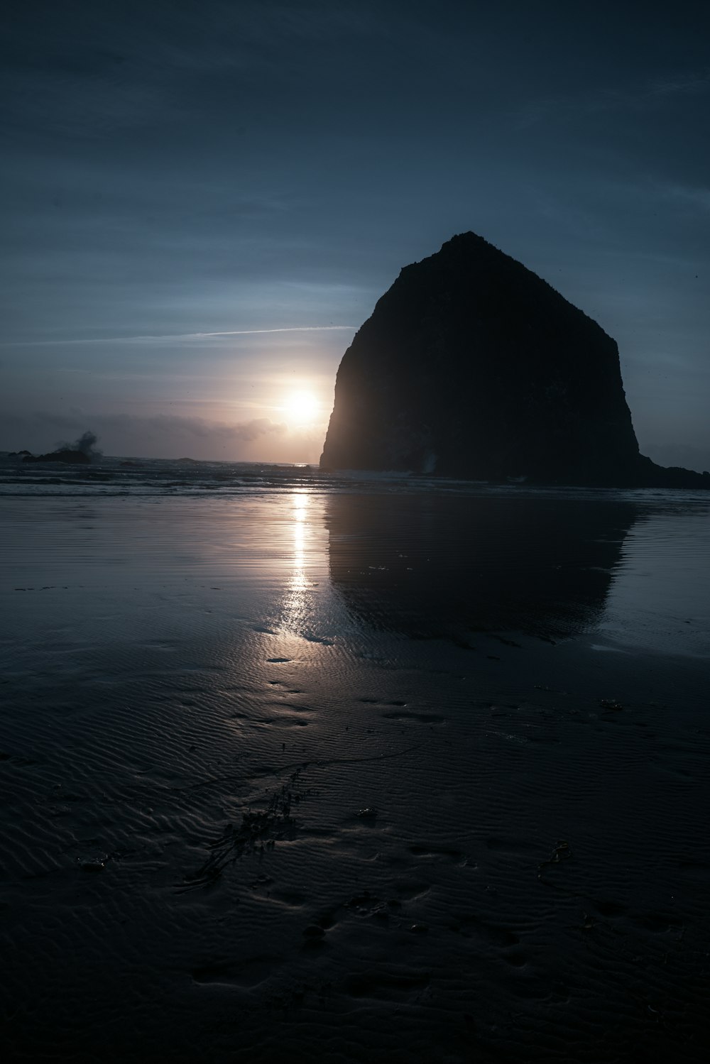 silhouette of rock formation on sea during sunset