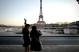 woman in black coat standing near eiffel tower during daytime