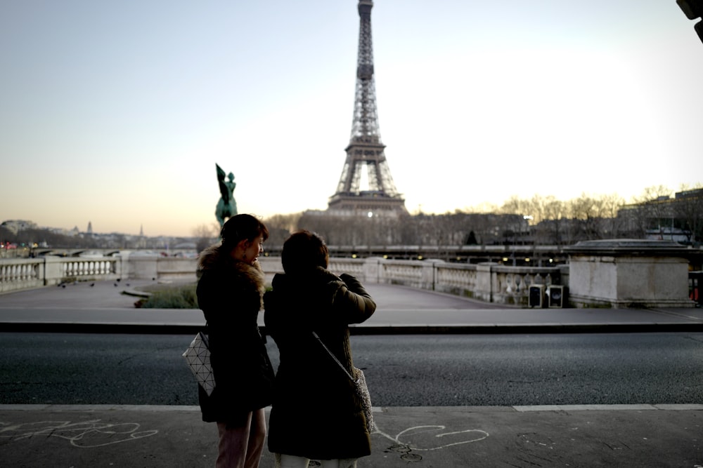 woman in black coat standing near eiffel tower during daytime