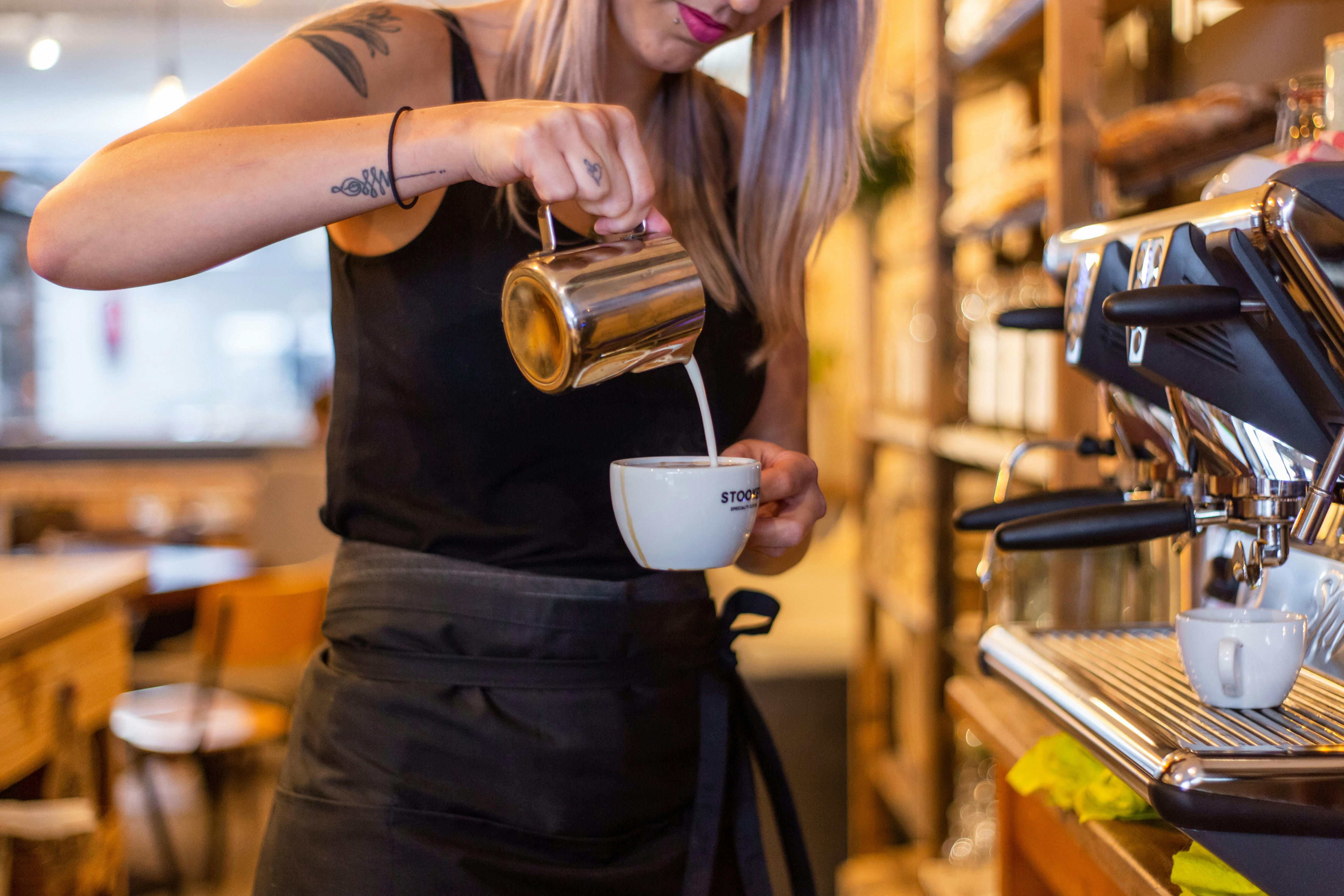 woman in black dress holding white ceramic mug