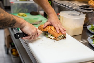Hands of a chef preparing a homemade sandwich with fresh ingredients.