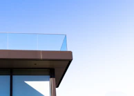 Side angle of a balcony with sturdy aluminum frames and clear glass.
