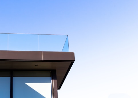 A close-up of a modern balcony with clear glass panels installed, showing the sleek finish.