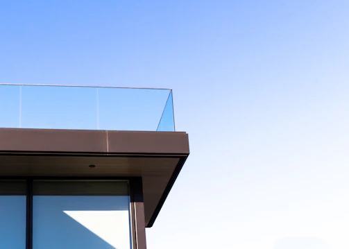 Wide shot of a modern balcony featuring polished stainless steel railings against a clear blue sky.