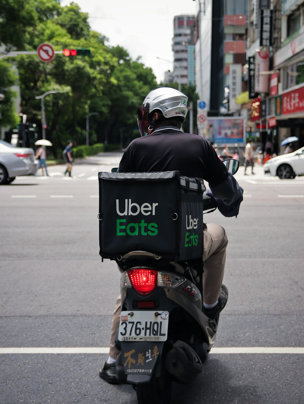 昼間の道路でバイクに乗る黒いジャケットの男