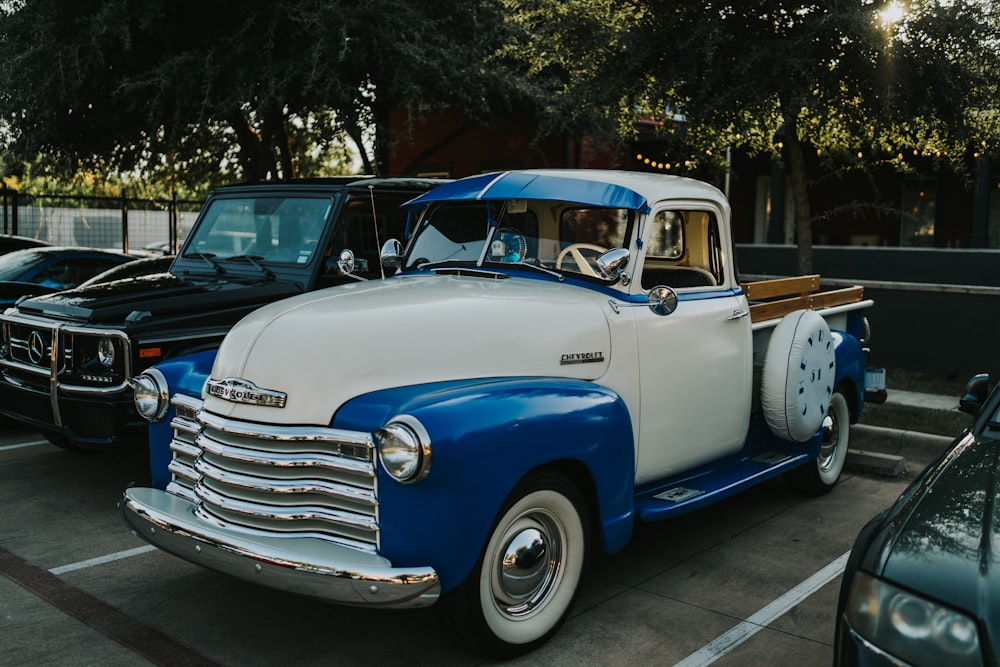 blue and white vintage car parked on gray concrete pavement during daytime