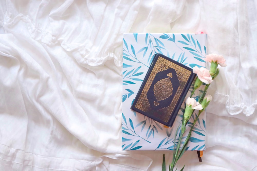 black and brown book on white and blue floral textile