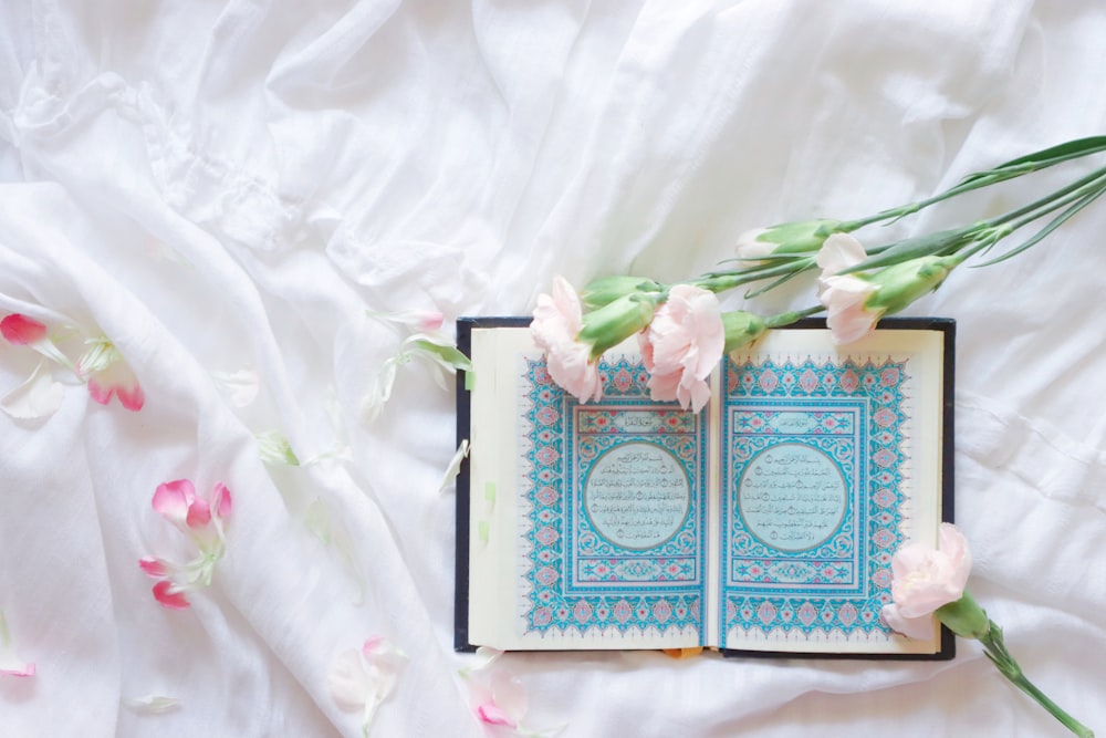 blue and white book on white and pink floral textile