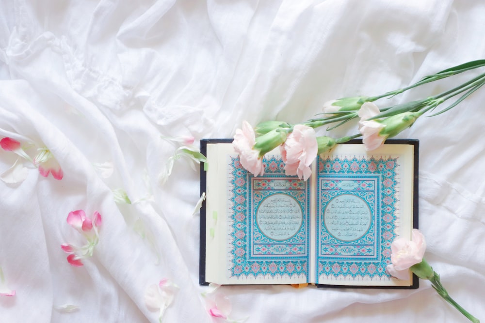 blau-weißes Buch über weißes und rosa Blumentextil