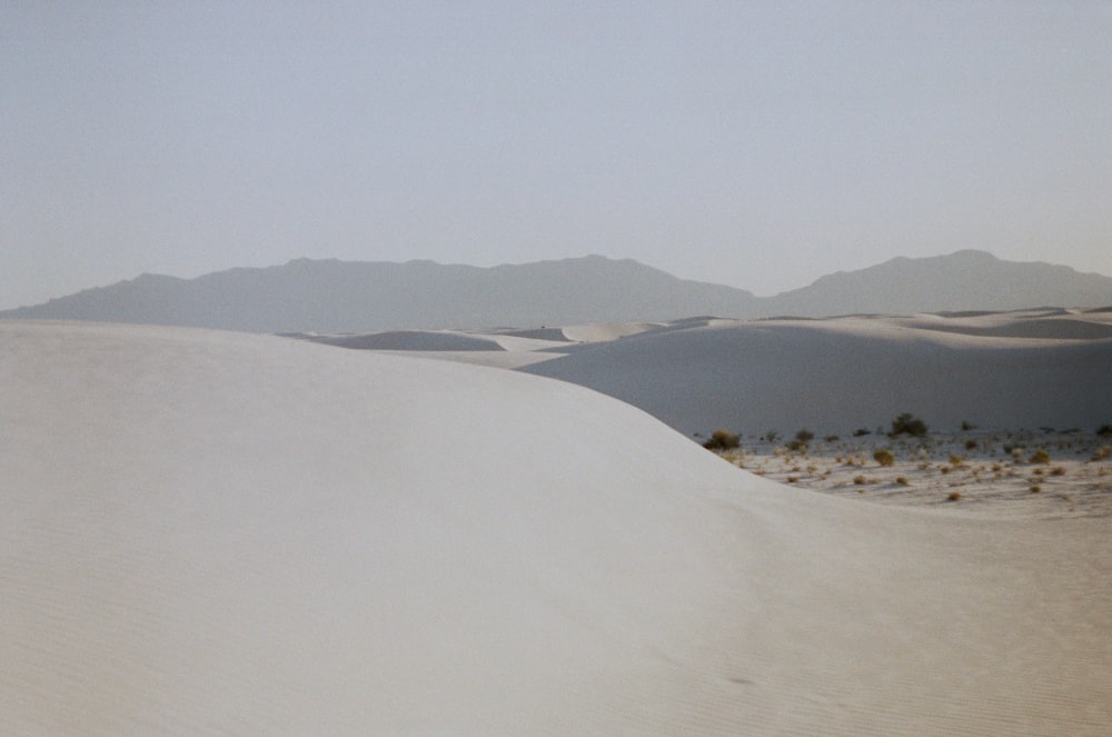 white sand with green grass and mountains in the distance