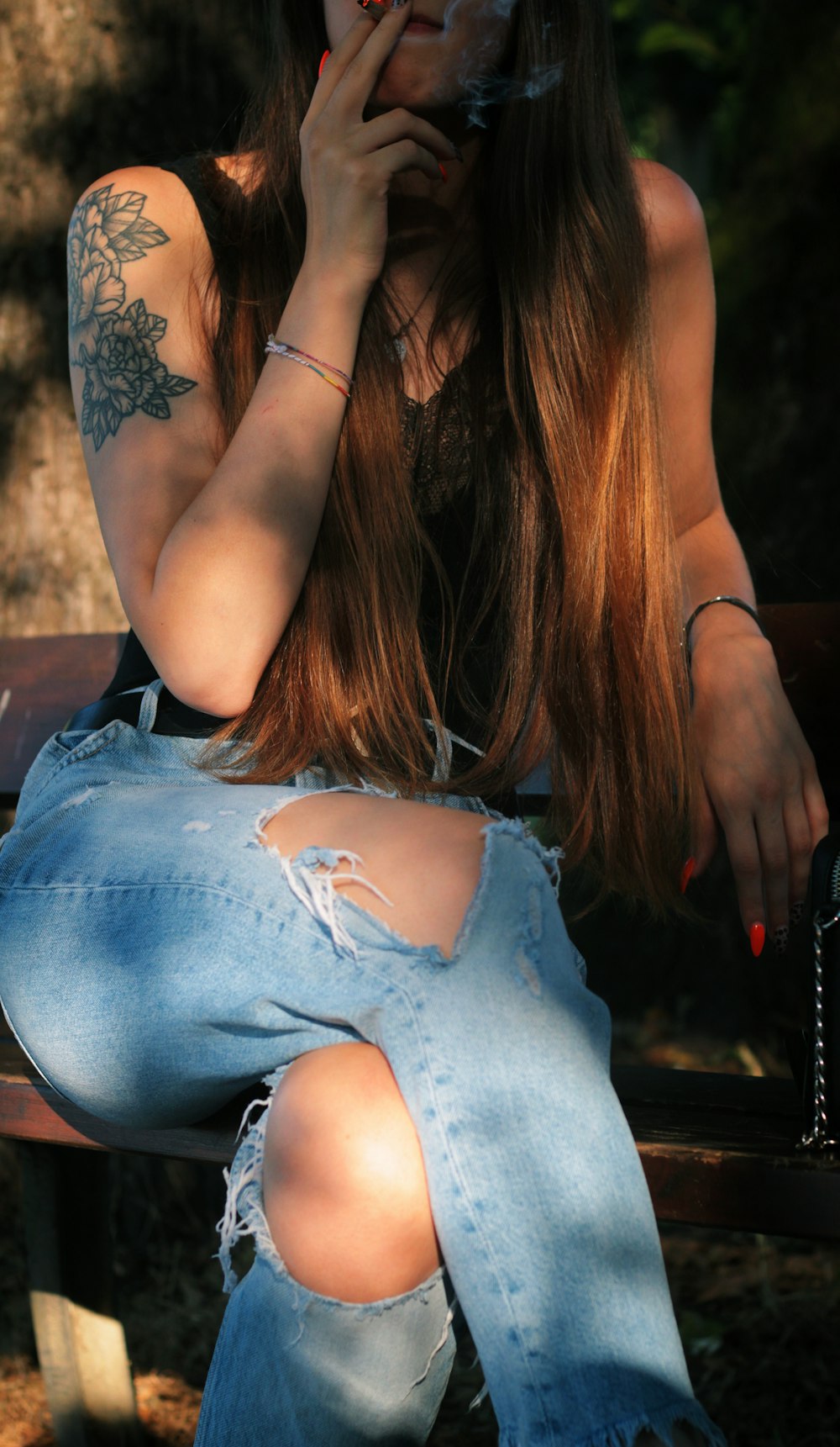 woman in blue denim shorts sitting on brown wooden bench