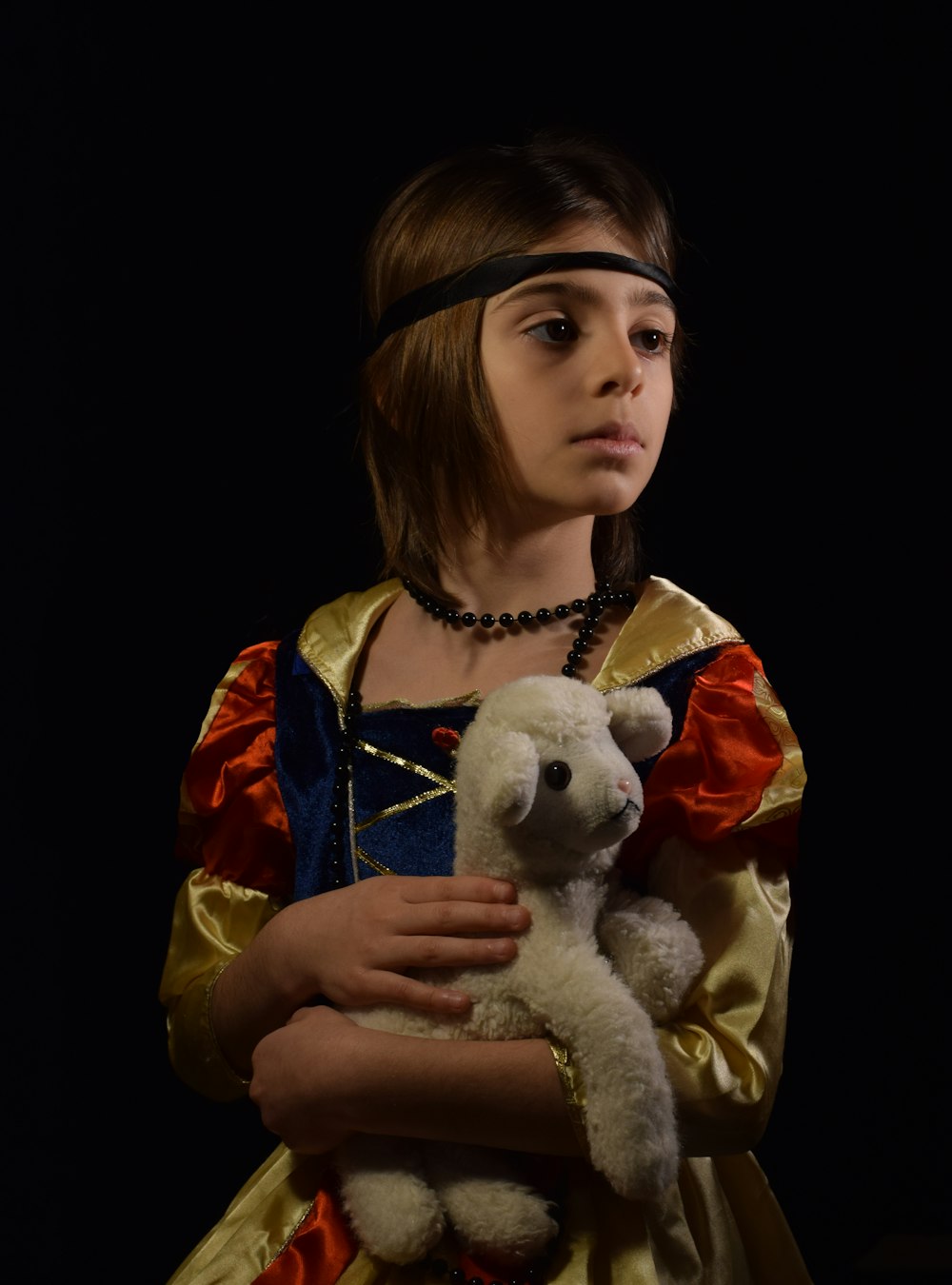 girl in red and yellow jacket holding white bear plush toy