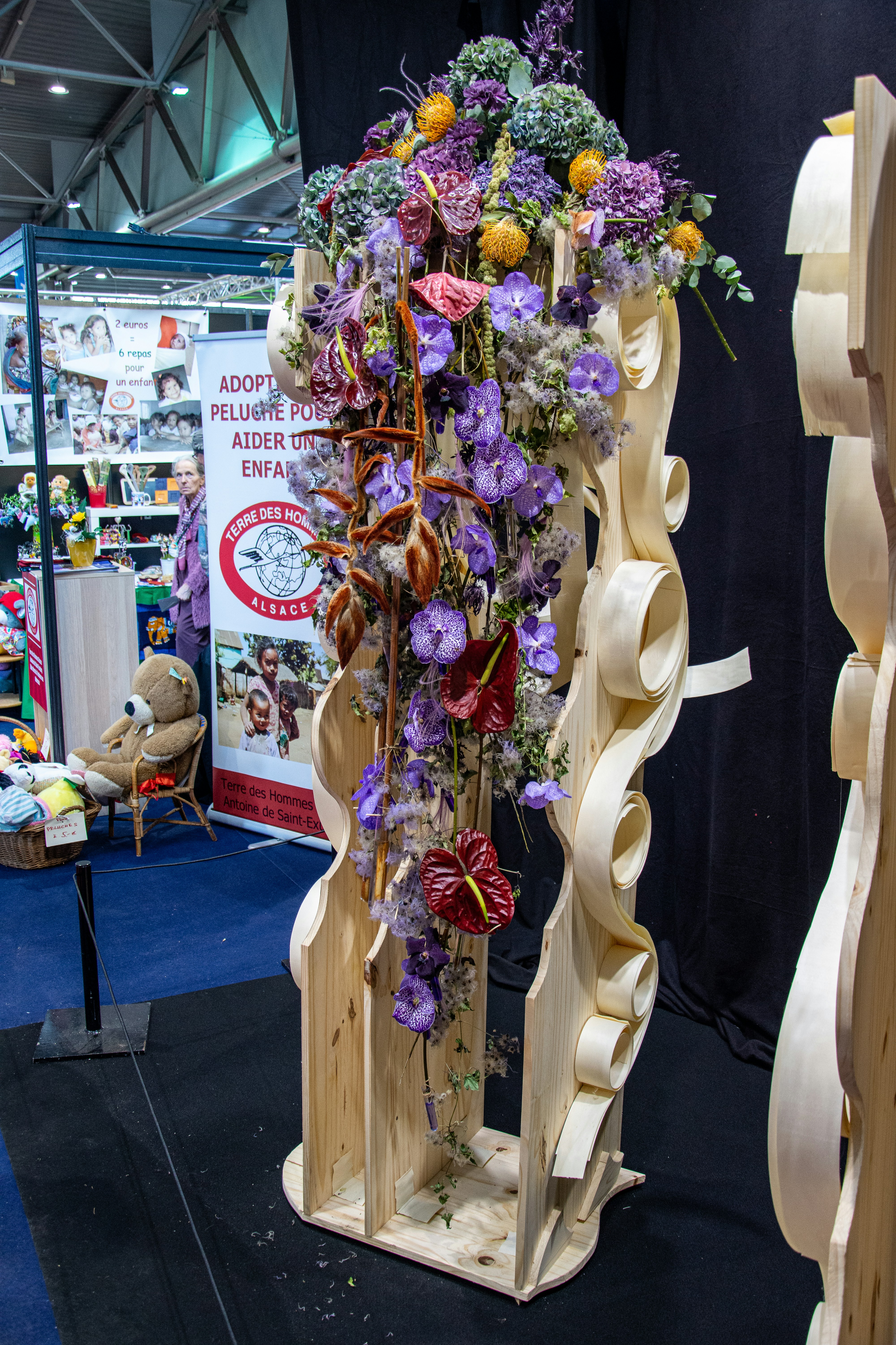 Lush floral installation with cascading blooms in warm tones suspended from a wooden frame
