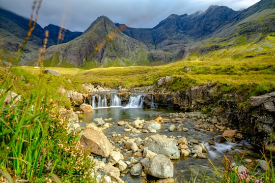 green grass field and green mountains during daytime in Fairy Pools United Kingdom