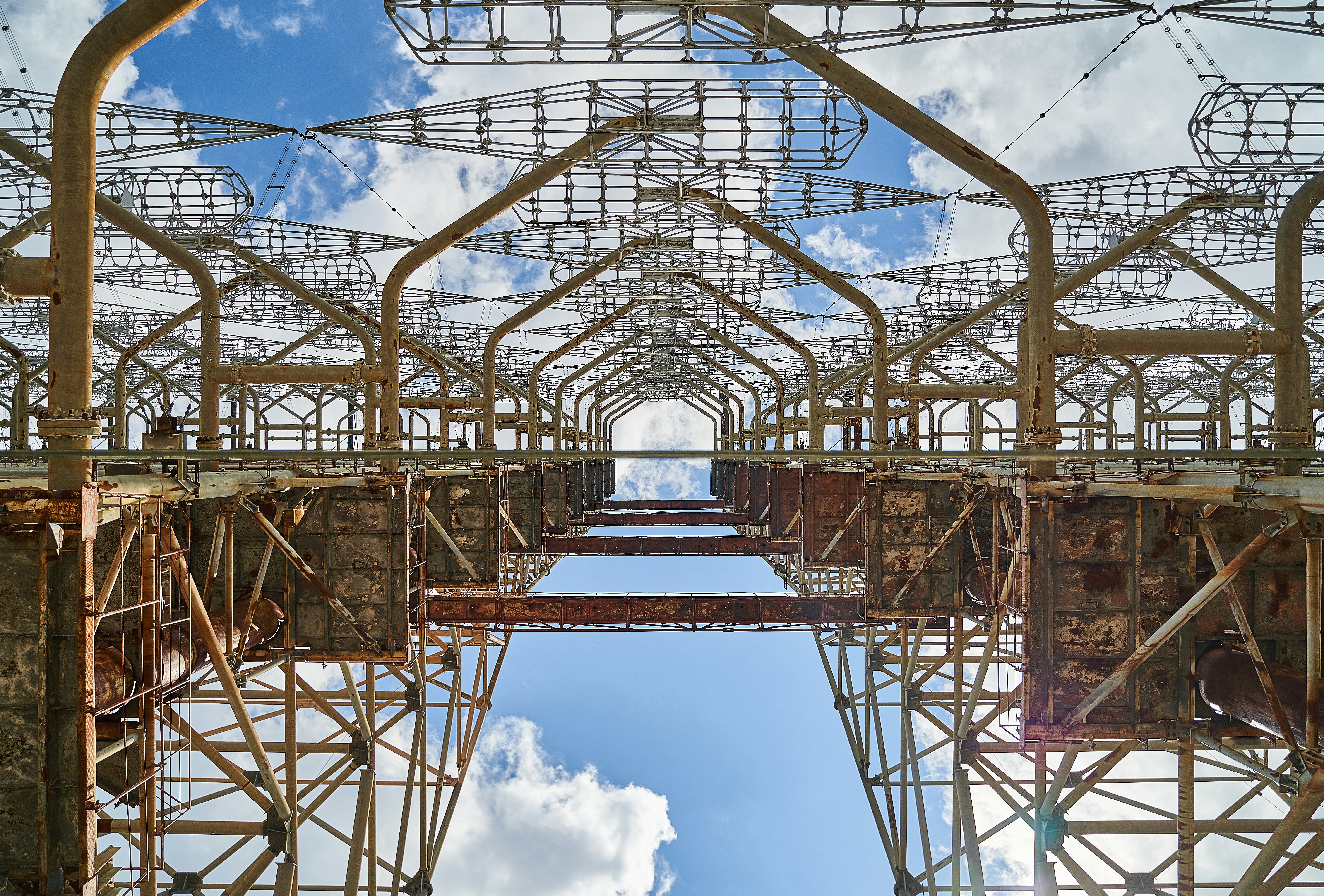 brown metal bridge under blue sky and white clouds during daytime