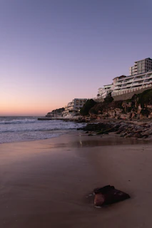 A cozy beachfront resort at dusk, with soft lights reflecting on gentle waves.