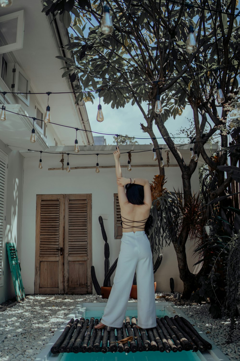 femme en pantalon blanc debout sur une échelle en bois marron
