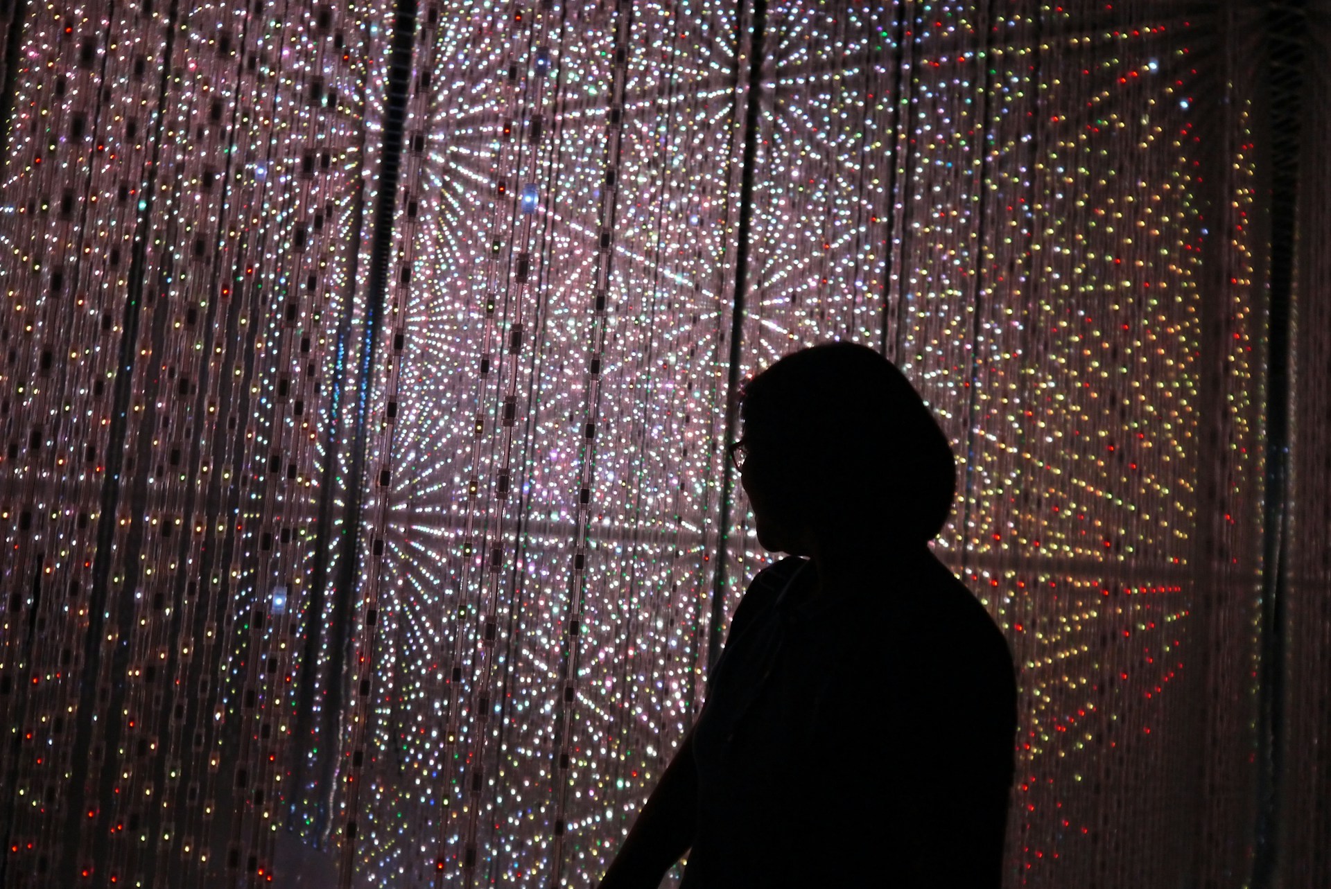 A silhouette of a person standing in front of a wall of lights