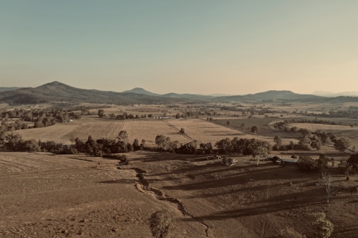 Wide shot of the family ranch landscape at golden hour, highlighting rugged hills and open skies.