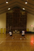 A badminton club banner hanging above a lively indoor court filled with players