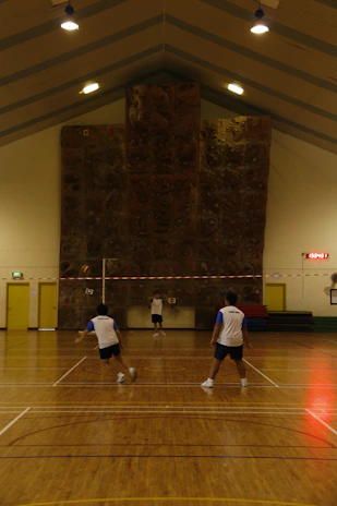 Seniors laughing together during a friendly badminton match in a bright gym.