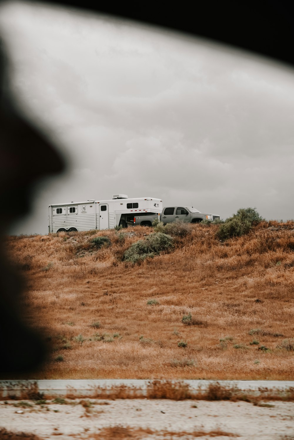 white rv trailer on brown grass field under gray cloudy sky during daytime