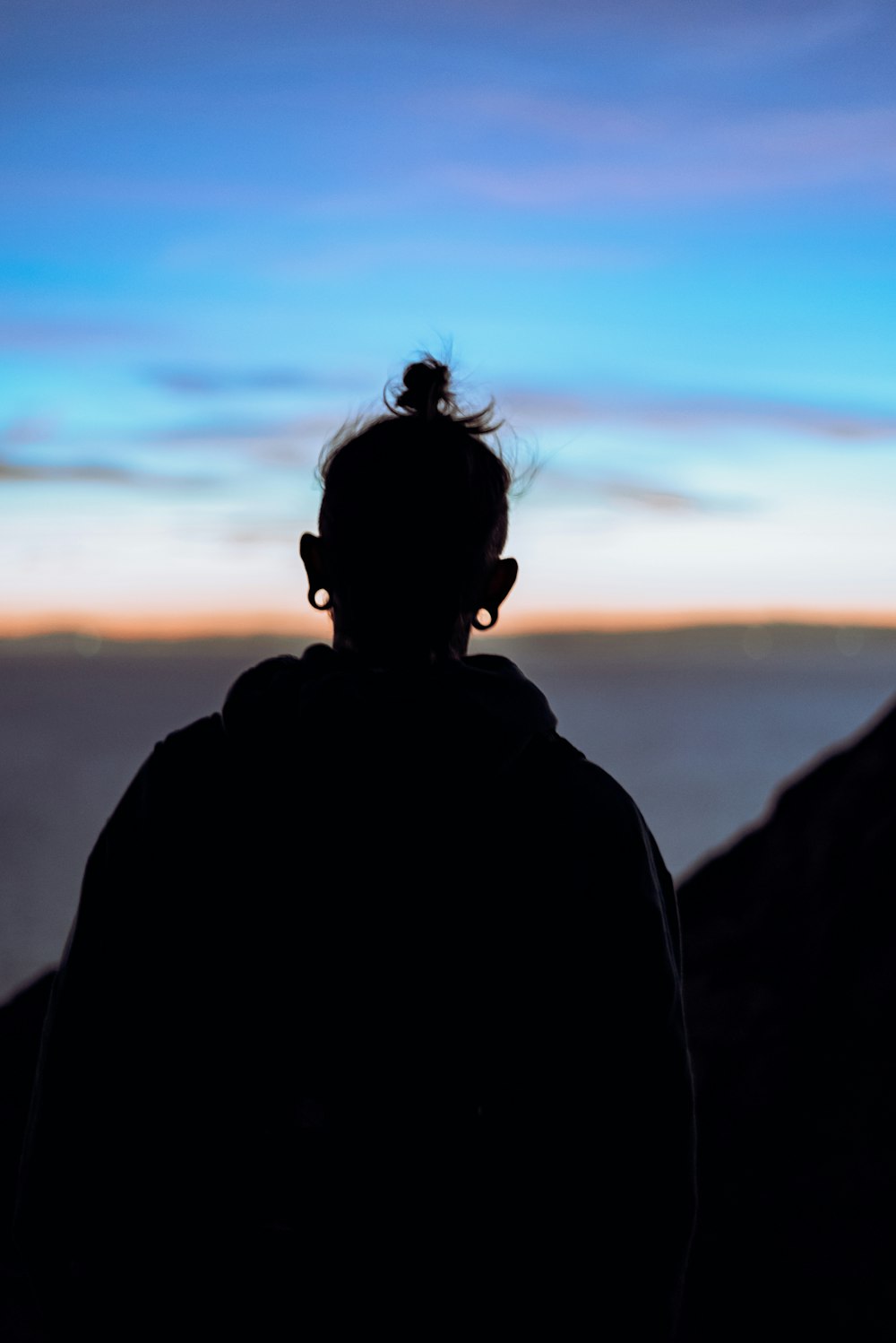 Silueta de la persona de pie en la roca durante la puesta del sol