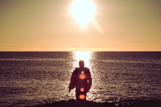man in black wet suit standing on sea shore during sunset in Guardamar Spain