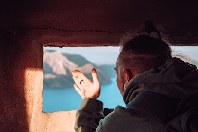 man in gray hoodie looking at the sea during daytime